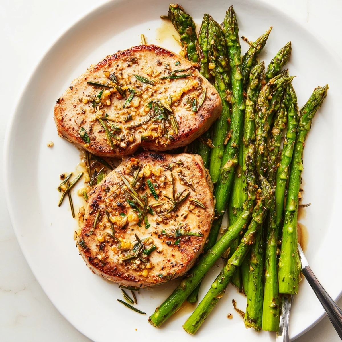 Golden-brown One-Pan Lemon Herb Pork Chops with tender asparagus, sizzling in a skillet ready to serve.