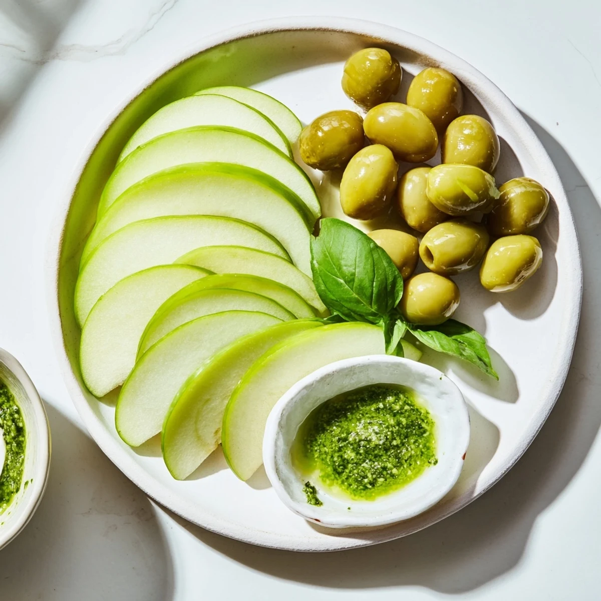 This Emerald City appetizer shows vibrant green olives and limes artfully arranged with pesto.