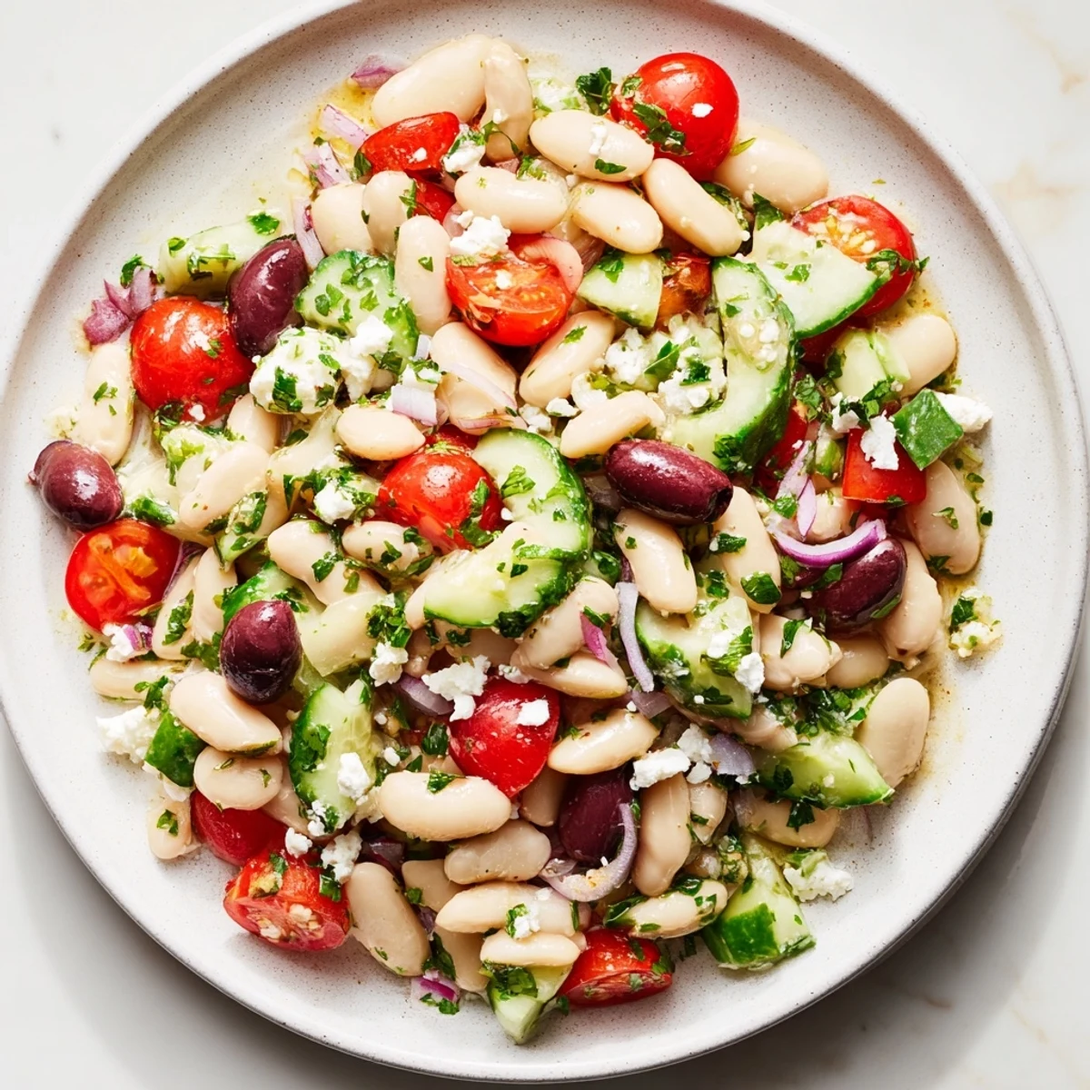 A close-up of a refreshing white bean salad, glistening with olive oil dressing.