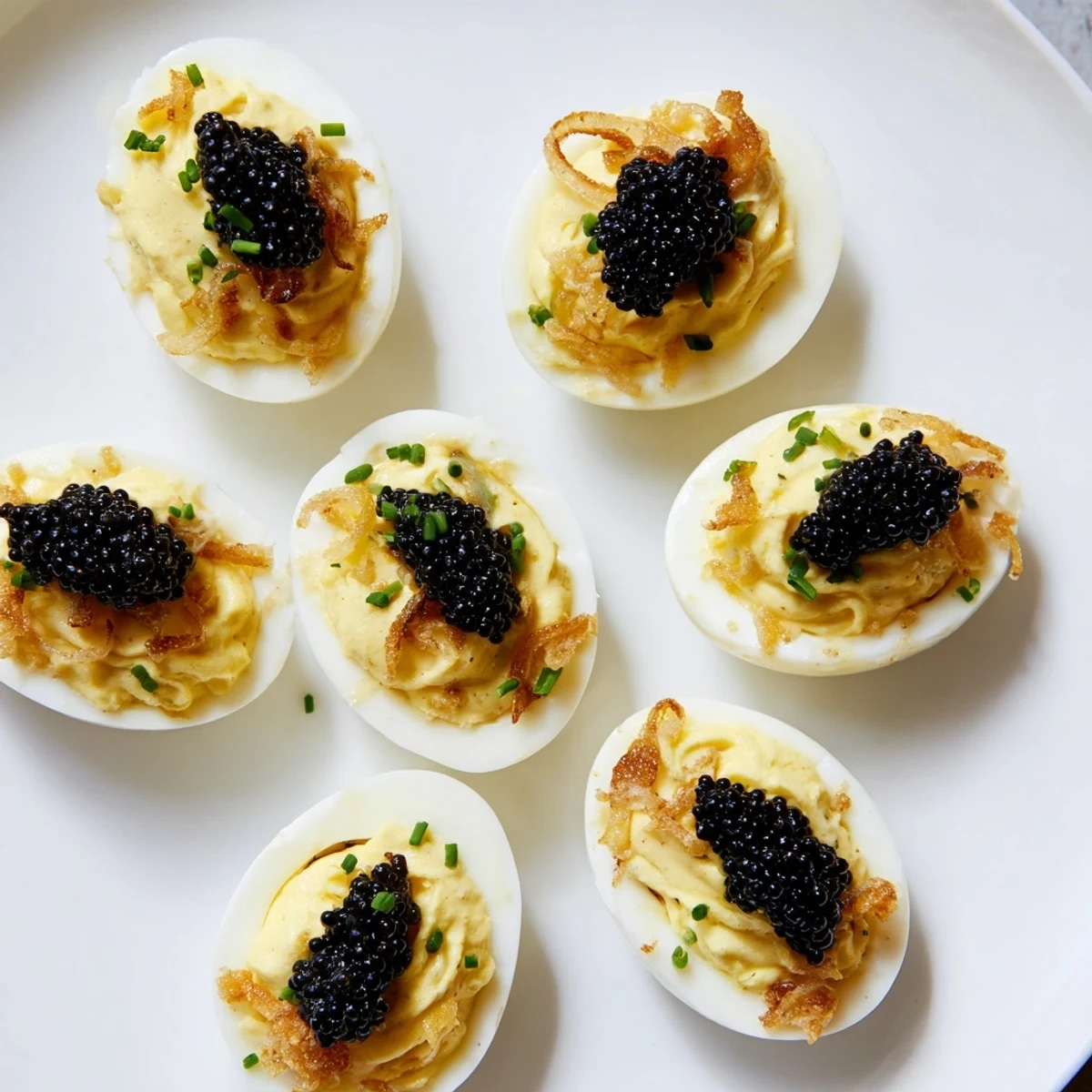 Elegant deviled eggs topped with glistening caviar and crunchy shallots, a gourmet appetizer.