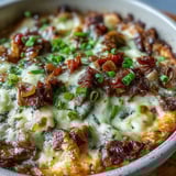 A warm Philly Cheesesteak Dip with sautéed peppers, onions, and tender shaved ribeye, ready for dipping.  