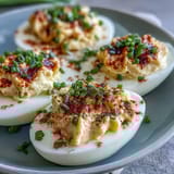 Classic deviled eggs with paprika and chives, creamy yolk filling piped into halved whites for a timeless appetizer.