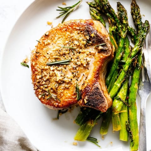 One-Pan Lemon Herb Pork Chops, surrounded by roasted asparagus and glistening lemon slices, a complete meal.