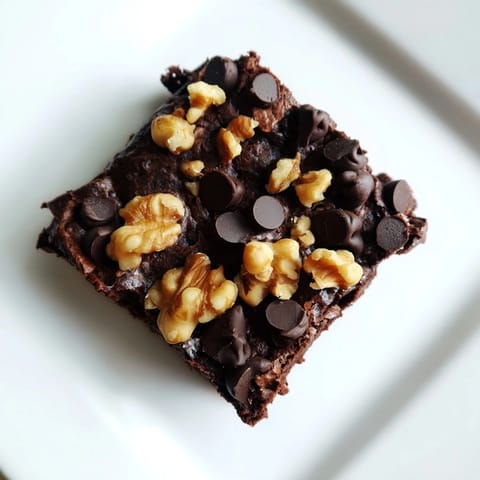 A close-up of thick, decadent Greek yogurt brownies, ready to be cut and served on a plate.