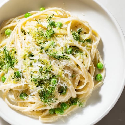 Freshly prepared creamy dill pasta, topped with bright green dill and Parmesan cheese ready to eat.