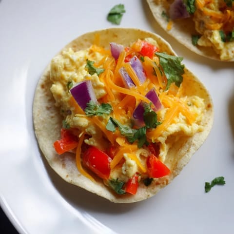 Baked sheet pan breakfast tacos overflowing with melted cheese and colorful bell peppers, ready to eat.