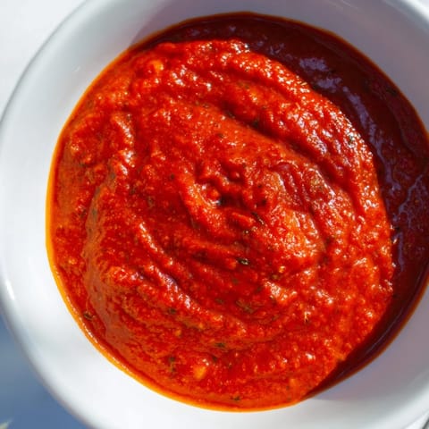 Close-up shot of creamy, blended hidden veggie tomato pasta sauce in a skillet, showing its smooth texture and vibrant red-orange color.
