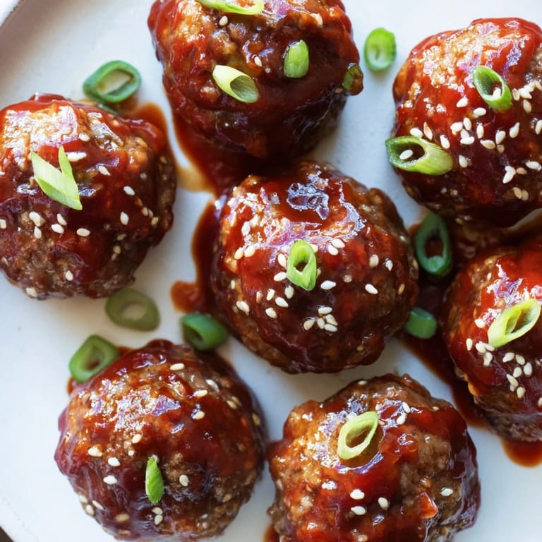 A close-up of Spicy Sriracha Honey Meatballs, showing the glistening glaze and sprinkled sesame seeds.