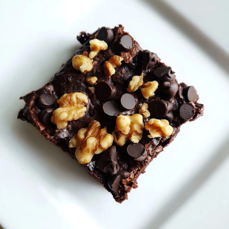 A close-up of thick, decadent Greek yogurt brownies, ready to be cut and served on a plate.