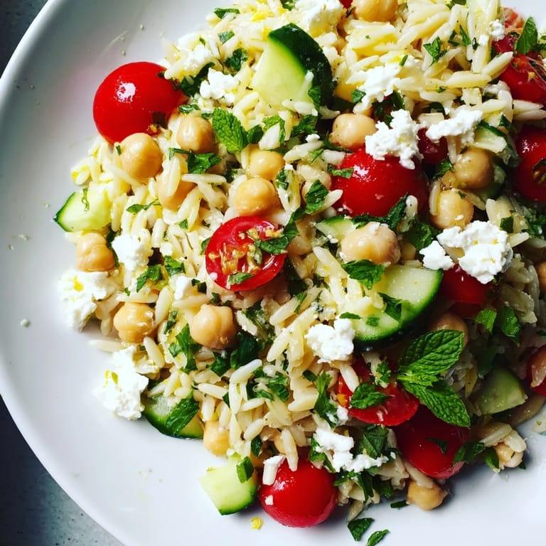 Lemony Chickpea Orzo Salad topped with crumbled feta and a lemon wedge, ready for a summer picnic.